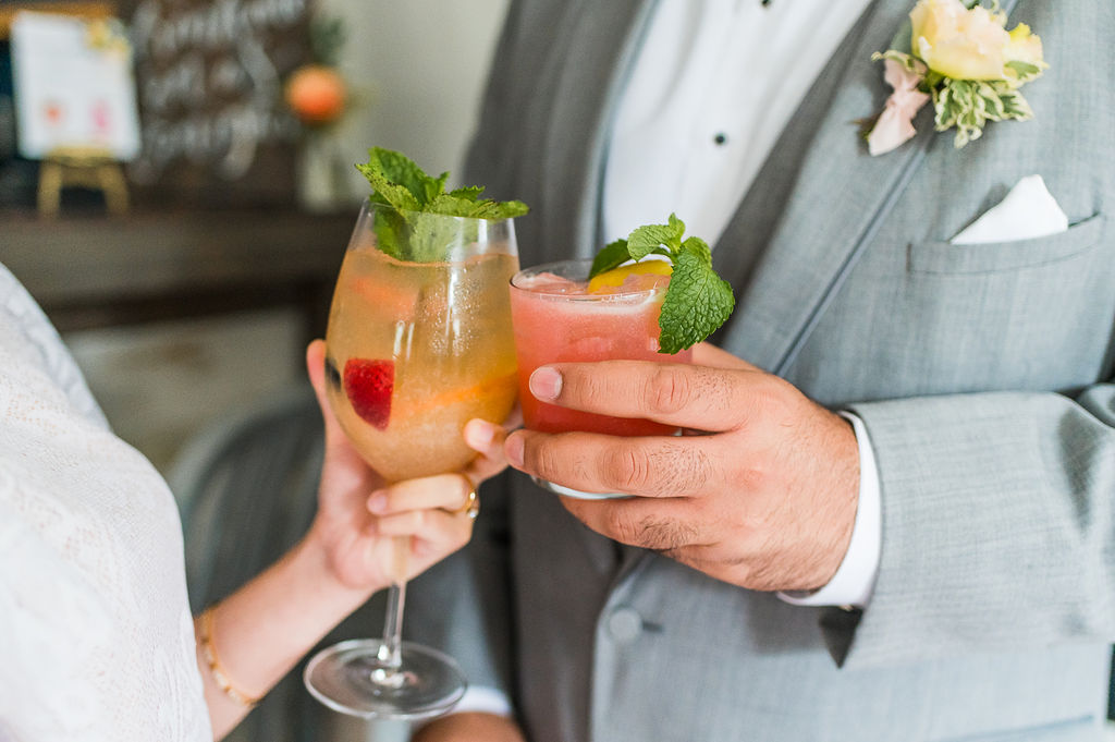 Wedding couple clinking glasses with their signature cocktail