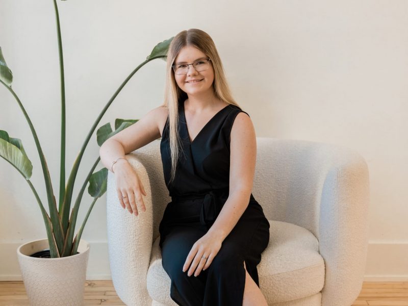 Wedding Planner in a black outfit sitting in a chair next to a green plant