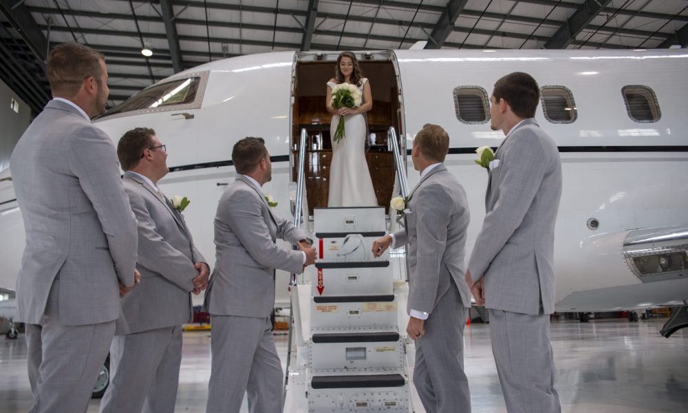 Groomsmen looking up at plane with bride standing in doorway