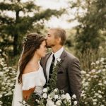 Groom kissing brides forehead in forest