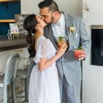 Bride and groom holding signature cocktails while kissing